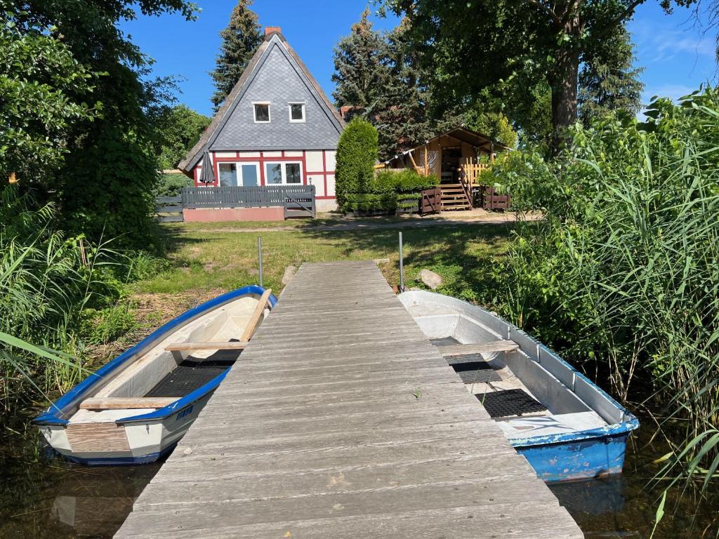 zwei Boote vor einem Haus angedockt in der Unterkunft Haus am See mit Steg, Boot, Kamin und Sauna - Mecklenburgische Seenplatte in Blankensee