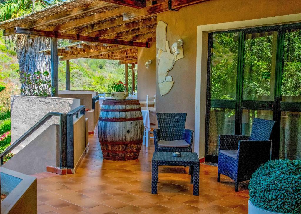 a patio with chairs and a barrel and a table at Hotel L'Oleandro in Villasimius