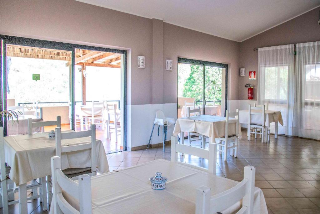 a dining room with tables and chairs and windows at Hotel L'Oleandro in Villasimius