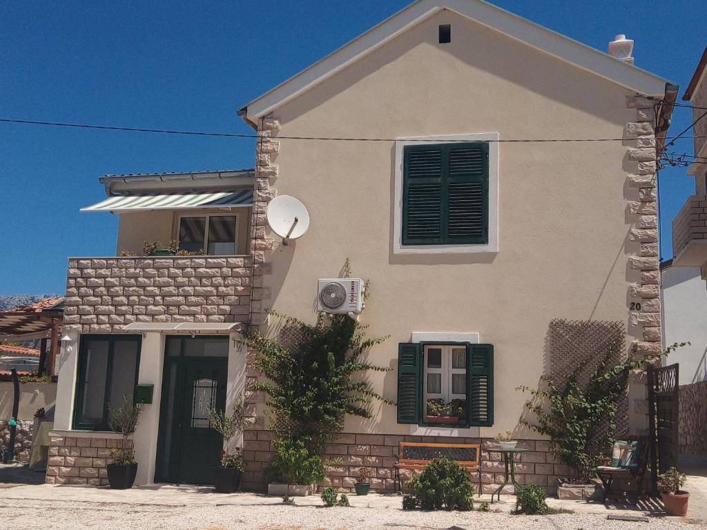 a white house with green shutters and a window at Apartment Milka in Vinjerac