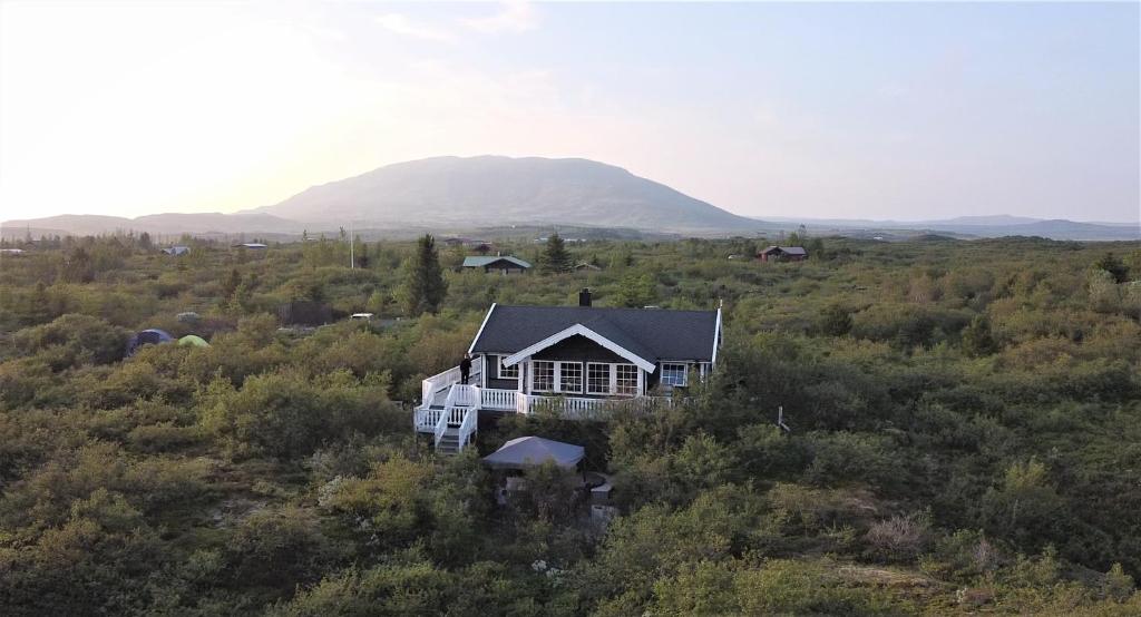 uma casa num campo com uma montanha ao fundo em Golden Circle Vacation Home with hot tub & fire place em Selfoss