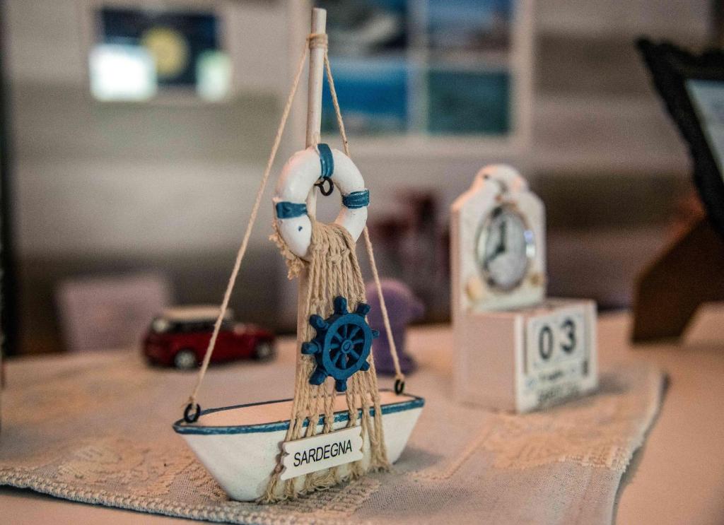 a small toy boat on a table with a clock at Hotel L'Oleandro in Villasimius
