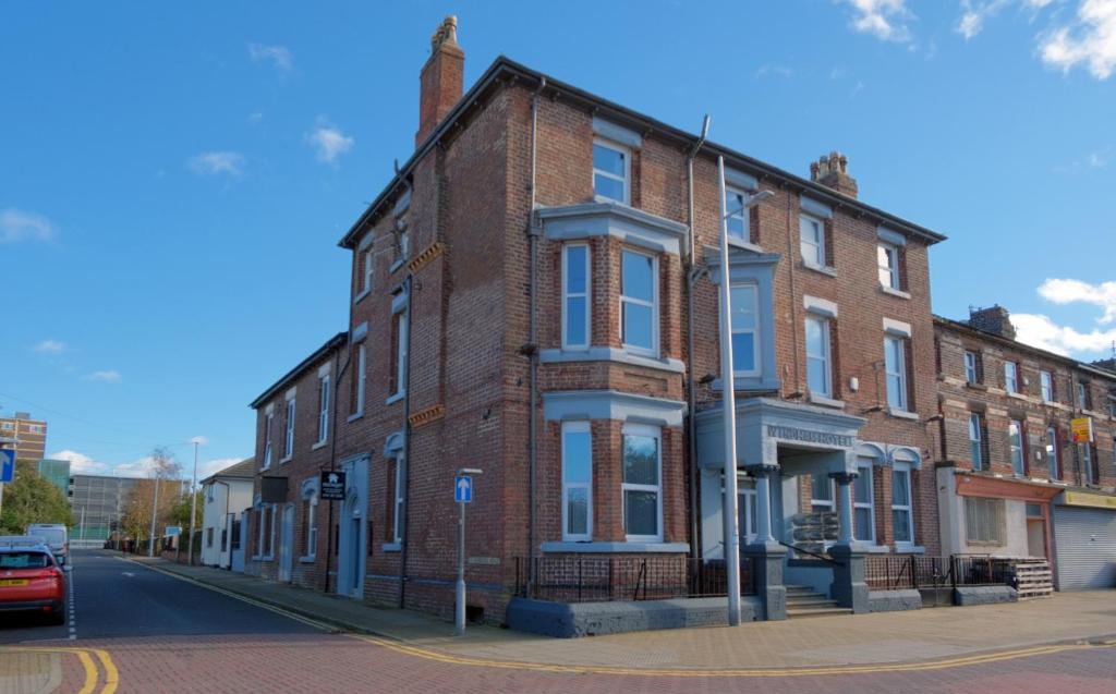 a brick building on the corner of a street at Windham ApartHotel by Serviced Living Liverpool in Litherland