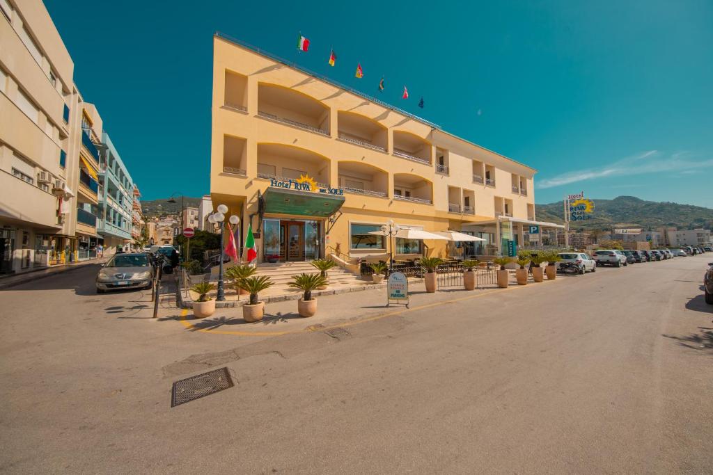 a large building on a city street with cars parked at Hotel Riva Del Sole in Cefalù