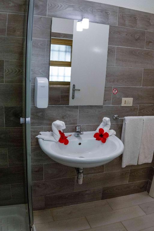 a bathroom with a sink and a mirror and towels at Hotel L'Oleandro in Villasimius