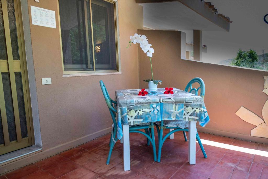 a blue table with chairs and a vase with flowers on it at Hotel L'Oleandro in Villasimius