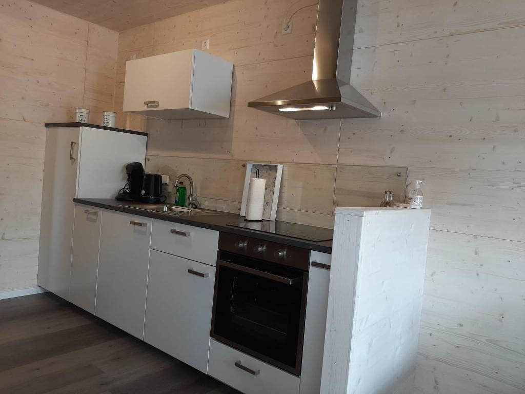 a kitchen with white cabinets and a stove and refrigerator at Hunsrück Chalet 