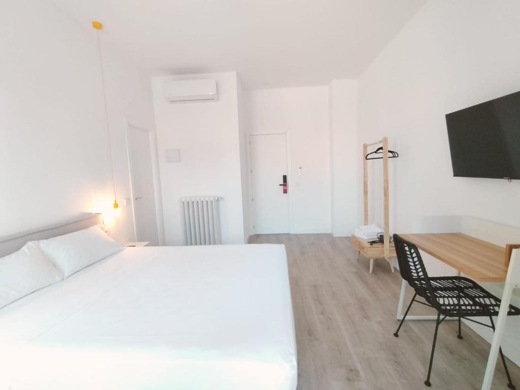 Dormitorio con cama, escritorio y TV en Hostal Manuela by gaiarooms, en Madrid