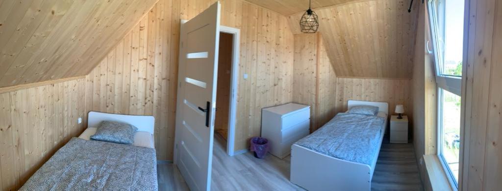 Duas camas num quarto com paredes de madeira em Domek Letniskowy Władysławowo em Władysławowo