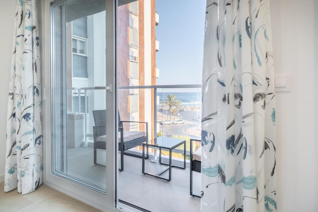 a room with a balcony with a view of the ocean at Global Properties, Bonito apartamento en Urbanizacion Ciudad Mar in Puerto de Sagunto