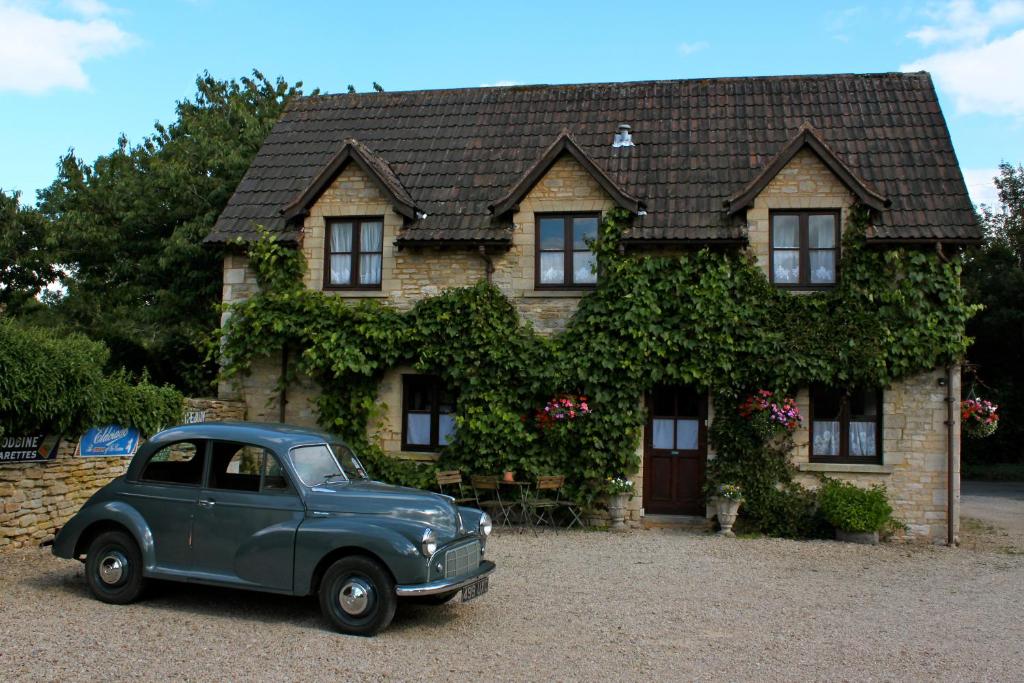 an old blue car parked in front of a house at Fosse Farmhouse Holiday Cottages in Chippenham