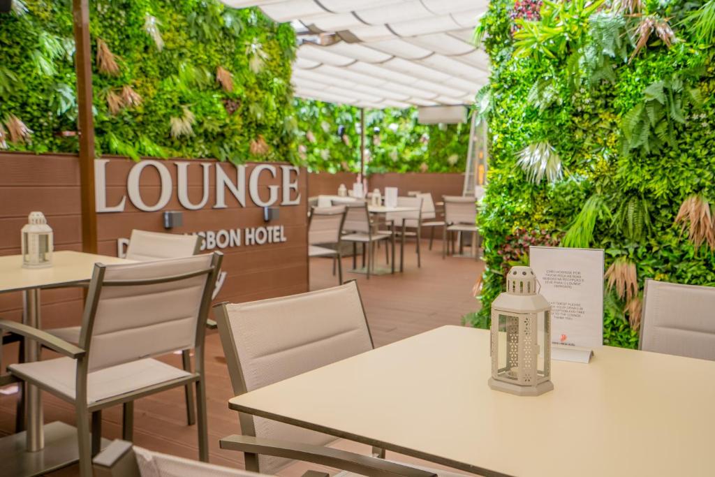 リスボンにあるDinya Lisbon Hotelのテーブルと椅子、緑の壁があるレストラン