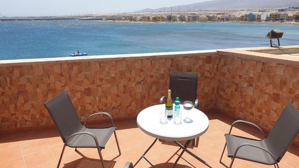 una mesa y sillas en un balcón con vistas al agua en CanariasBrisaMar - Apartamento en Arinaga