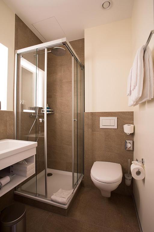 a bathroom with a shower and a toilet and a sink at Kreuz Bern Modern City Hotel in Bern