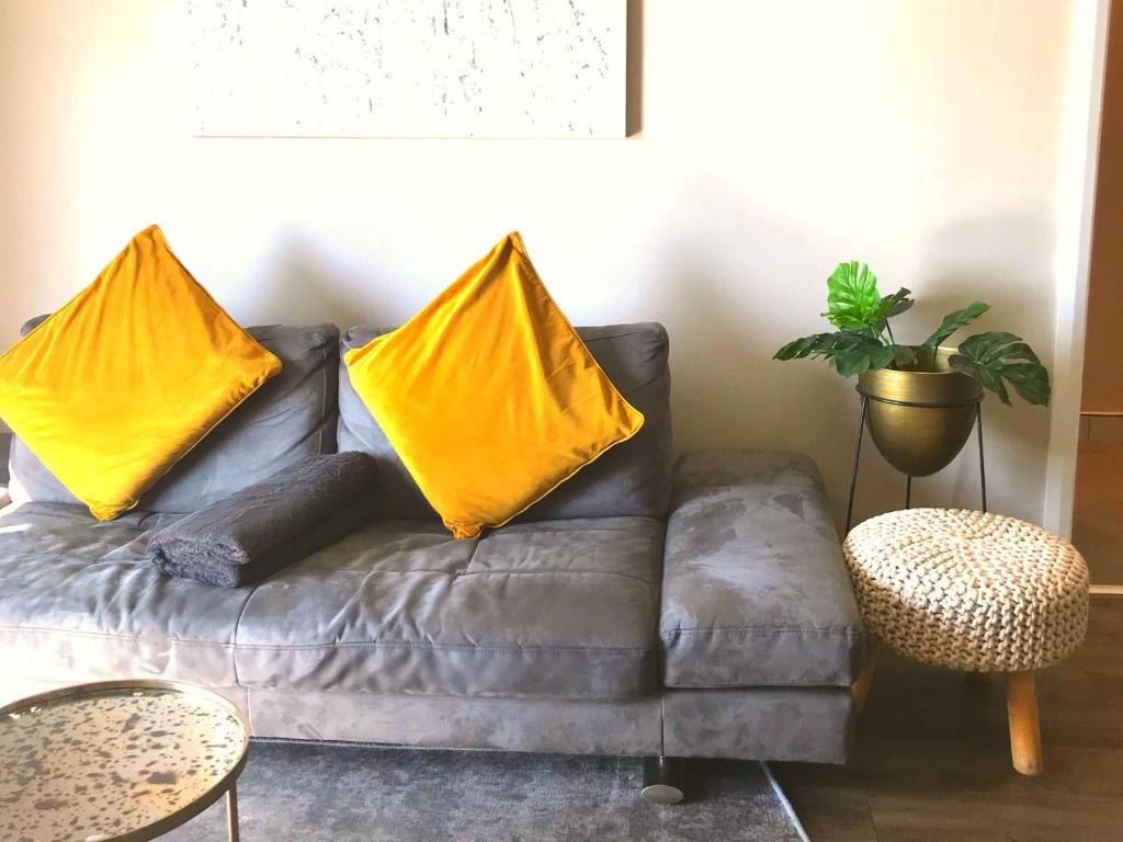 a gray couch with two yellow pillows on it at Menlyn Residence - Luxury Six Sleeper in Pretoria