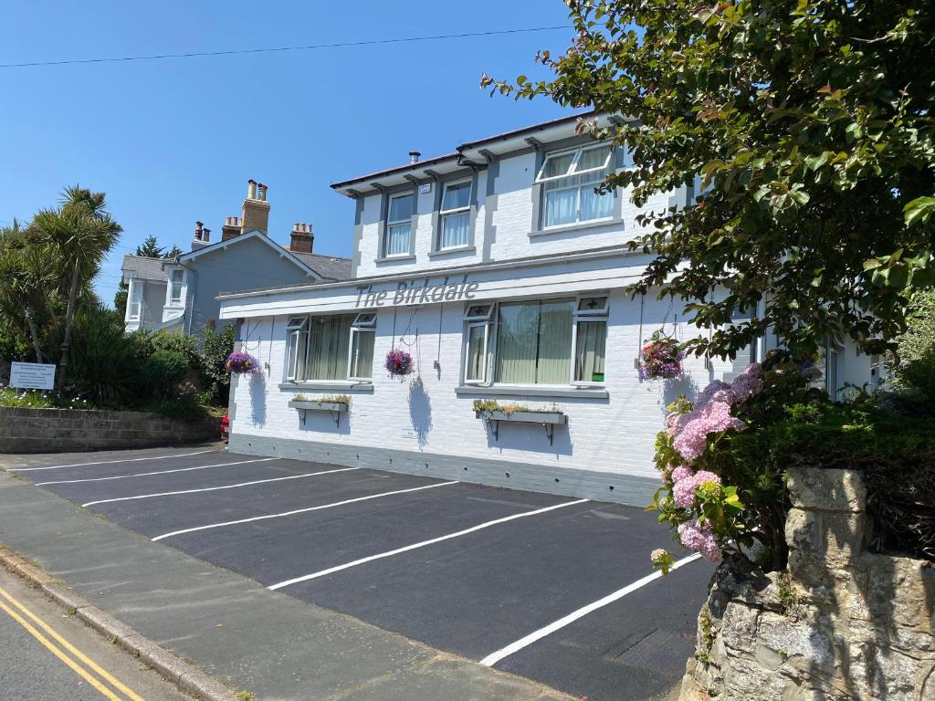 un edificio blanco con un estacionamiento delante de él en Birkdale Guest House en Shanklin