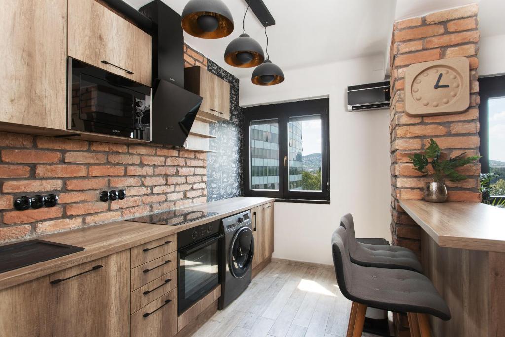 una cocina con armarios de madera y una pared de ladrillo en Industrial Studio, en Budapest