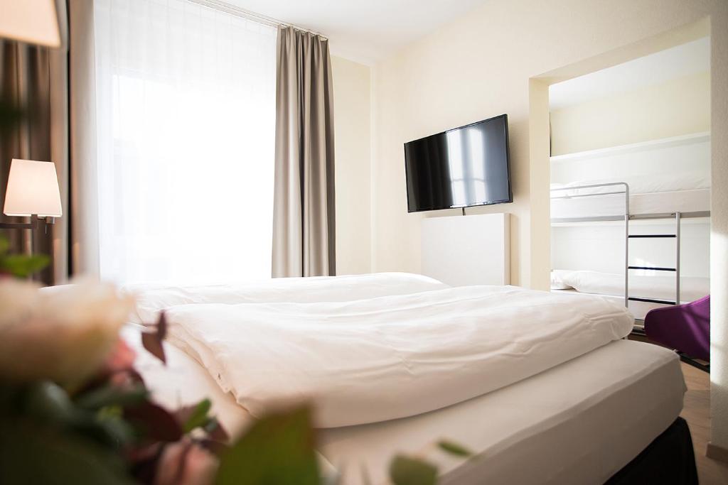 a hotel room with a bed and a tv on the wall at Kreuz Bern Modern City Hotel in Bern