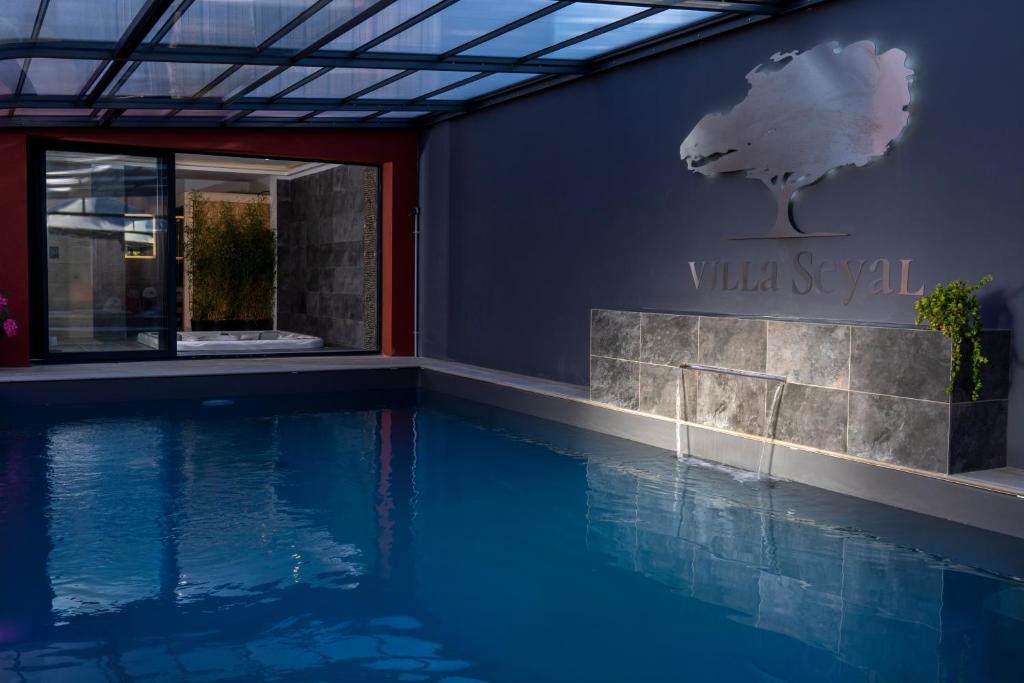 勒芒的住宿－Villa Seyal - avec piscine - jacuzzi - sauna & climatisation，带有别墅咒语标志的游泳池