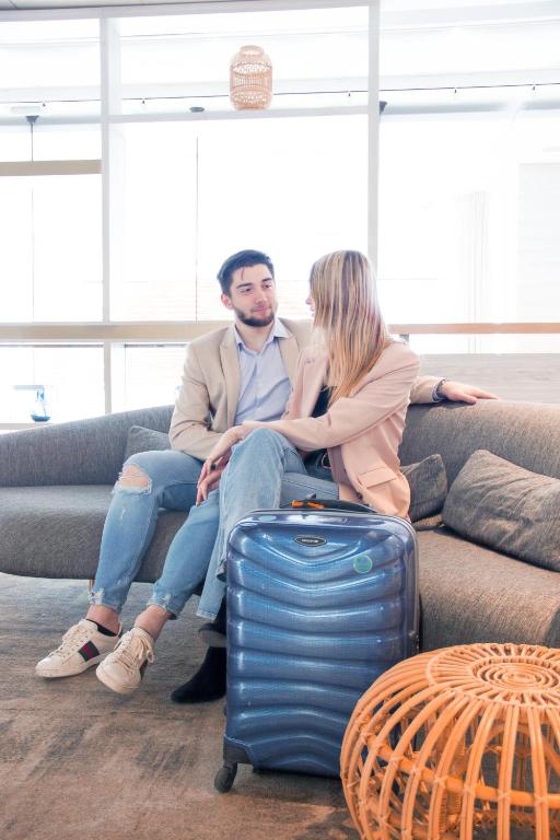 a man and a woman sitting on a couch with a suitcase at Novotel Monte-Carlo in Monte Carlo