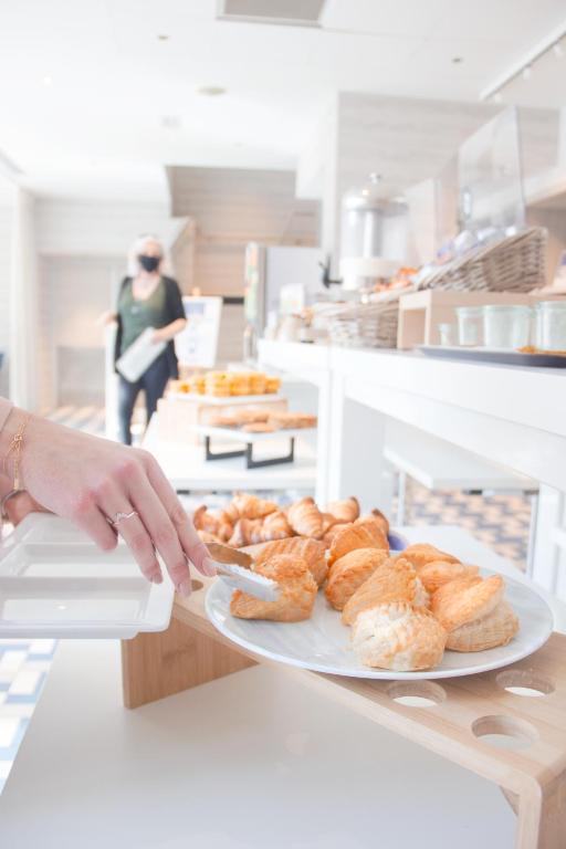 a person holding a plate of pastries on a counter at Novotel Monte-Carlo in Monte Carlo
