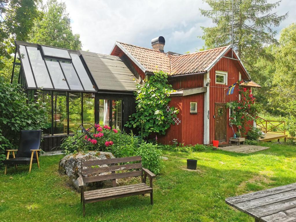 czerwony dom z ławką przed nim w obiekcie Unique holiday home in Mankarbo, Uppsala 