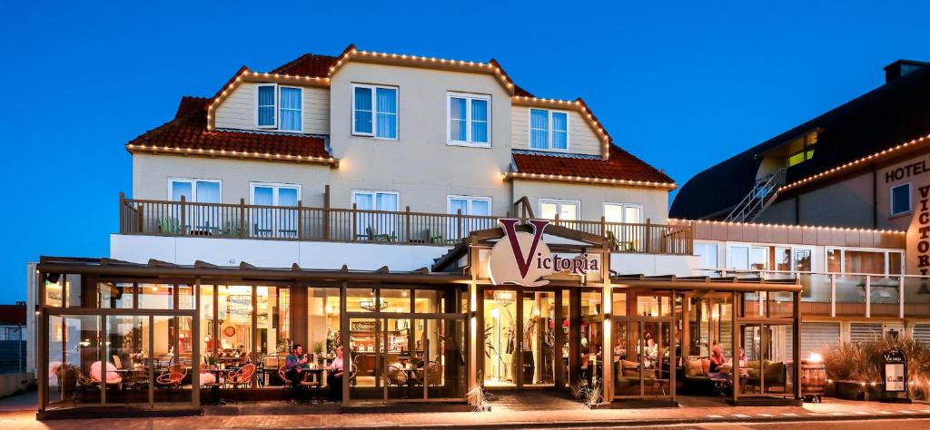 Un bâtiment avec des personnes assises à l'extérieur dans l'établissement Hotel Victoria, à Bergen aan Zee