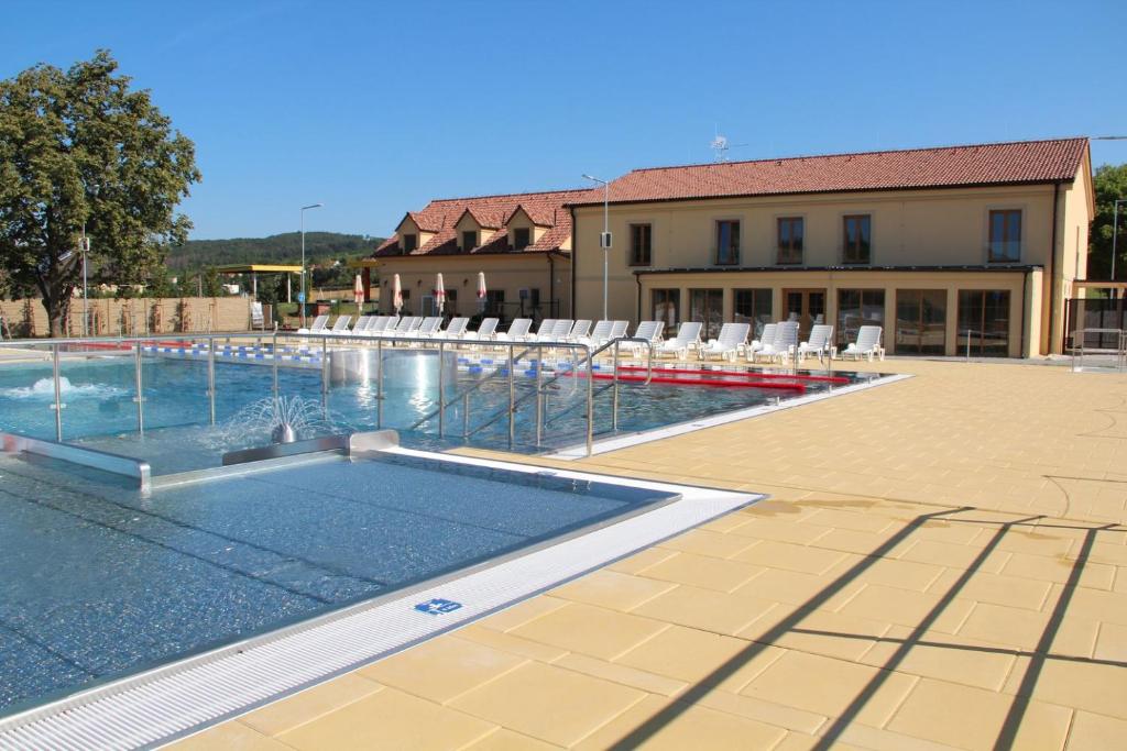 a swimming pool with chairs and a building at Resort Rybníček in Blatnice