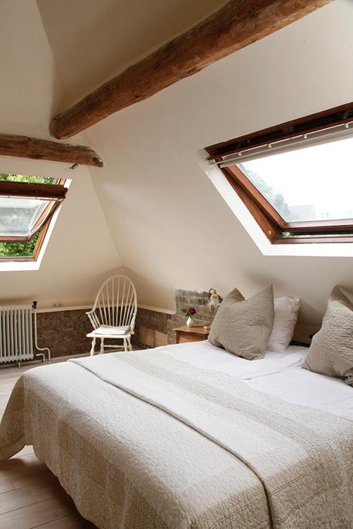 een slaapkamer met een groot bed en 2 ramen bij Annelies'Place to B& B in Maastricht