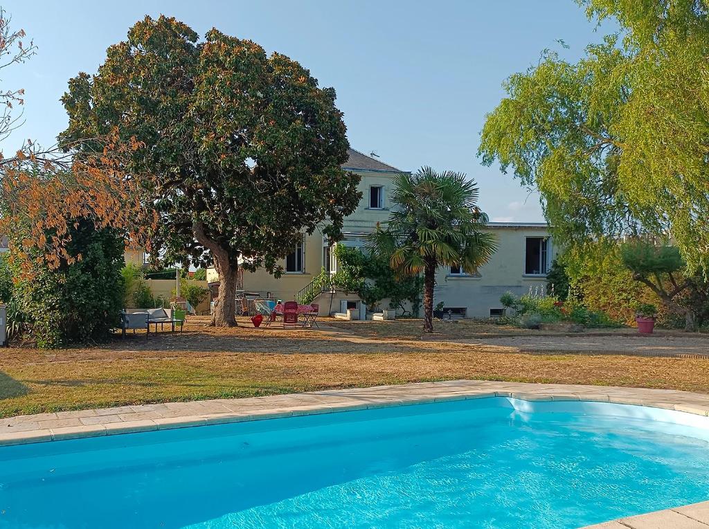 a blue swimming pool in front of a house at Le Magnolia, chambre d'hôte au calme in Saumur