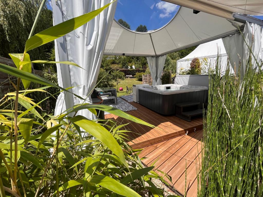 bañera de hidromasaje en una terraza de madera en una tienda blanca en Lodge spa privatif Starlette, séjour zen, en Meisenthal