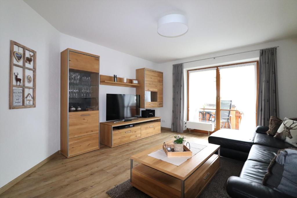 a living room with a couch and a tv at Landhaus Am Schelmenhag 13a in Oberstdorf