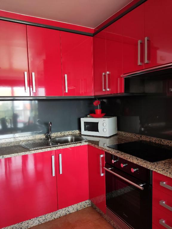 a red kitchen with a sink and a microwave at Apartamento Agarimo - La tranquilidad de una isla de menos de 5000 habitantes in Isla de Arosa