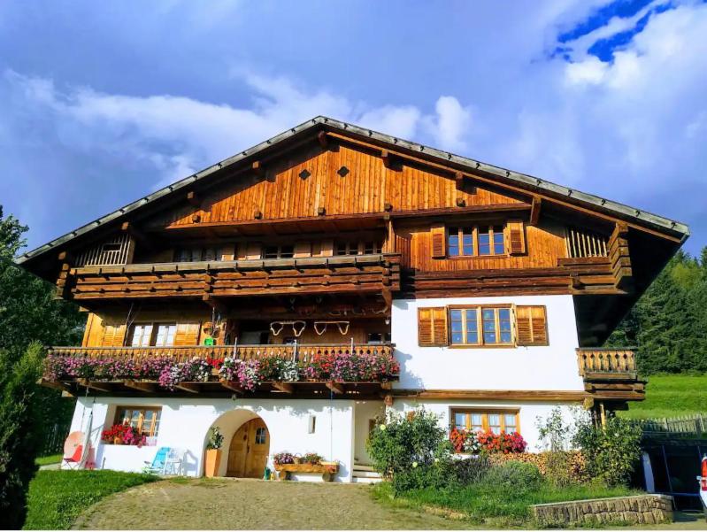 a wooden house with a balcony with flowers on it at Un bel panorama in un ambiente famigliare in Tesero