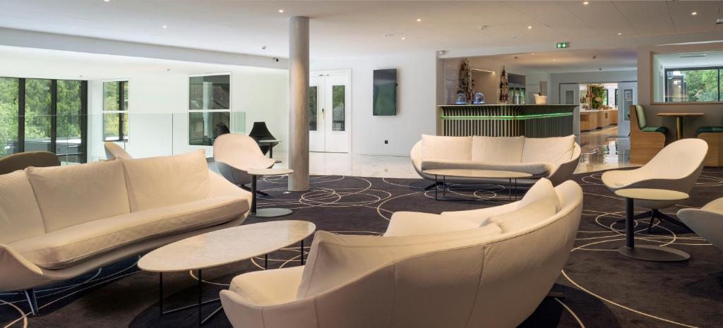 a lobby with white furniture and tables and chairs at 6717 Nature Hôtel &amp; Spa Le Clos des Délices in Ottrott