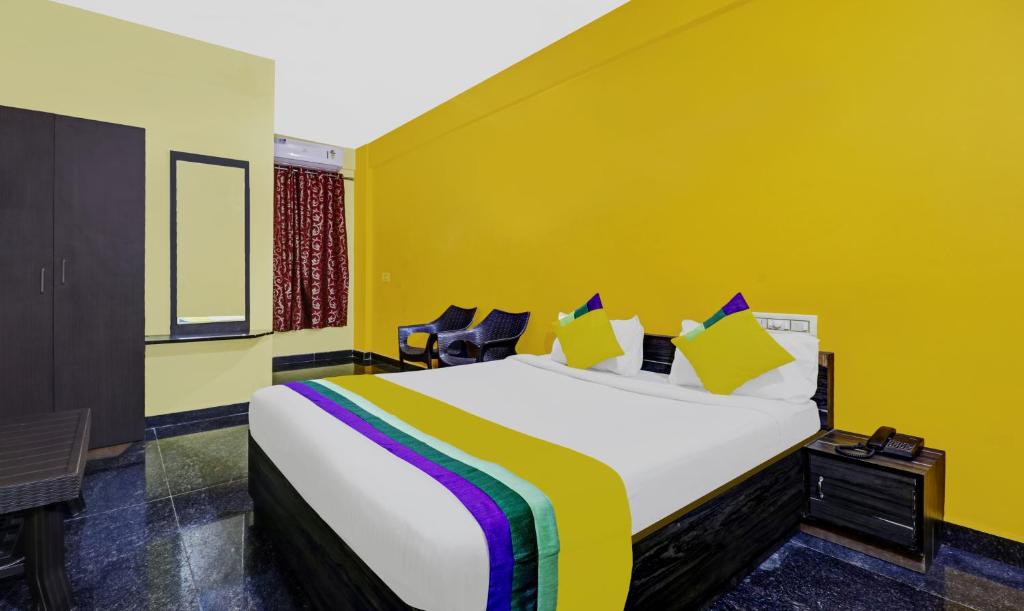 a bedroom with a large bed with yellow walls at Itsy By Treebo - Aravind Premiere Kushalnagar in Madikeri