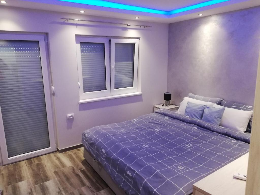 1 Schlafzimmer mit einem lila Bett und 2 Fenstern in der Unterkunft Extra Fruske in Vrdnik