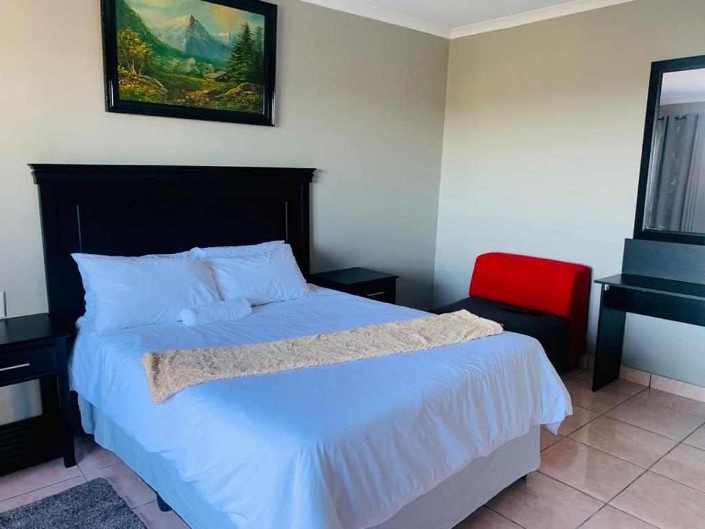 um quarto com uma cama e uma cadeira vermelha em Xaba Guest Lodge em Richards Bay