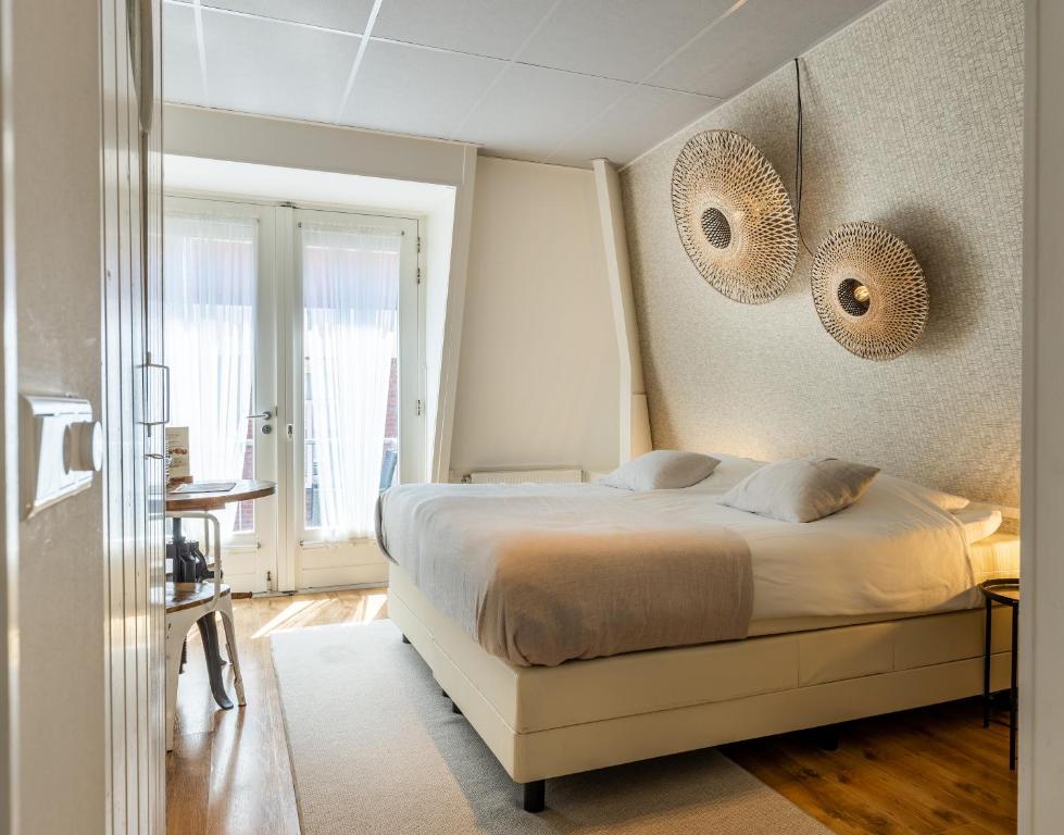 a bedroom with a bed with two mirrors on the wall at Hotel Pannenkoekhuis Vierwegen in Domburg
