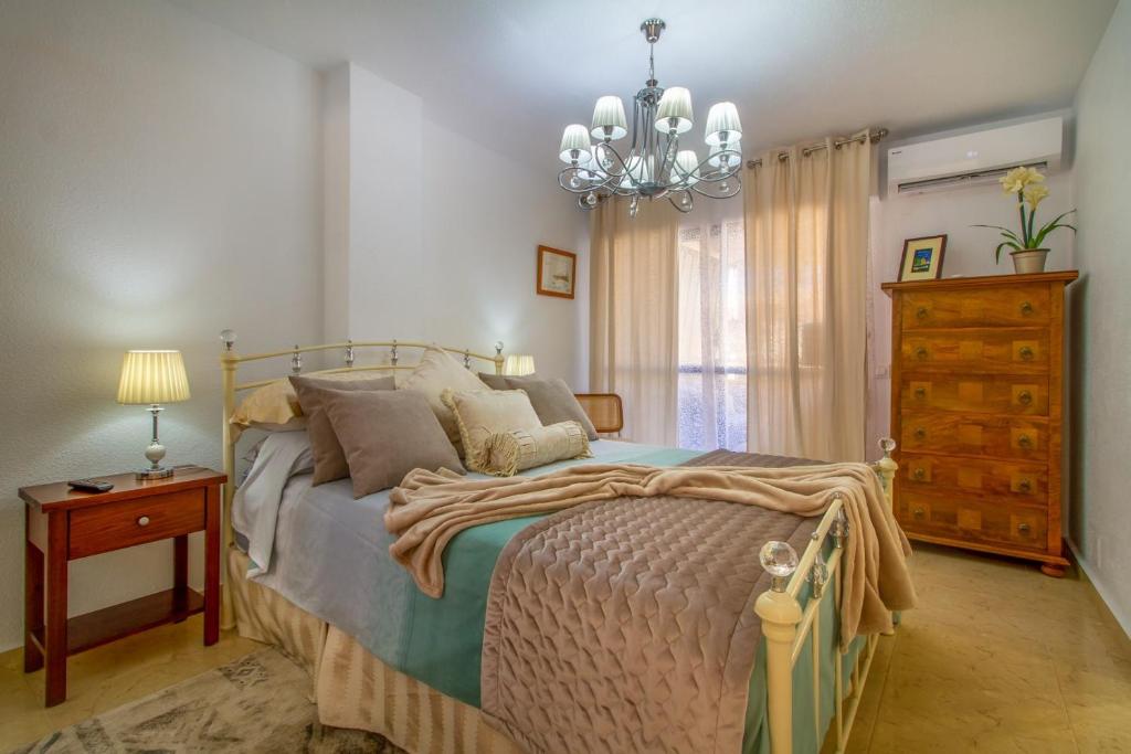 a bedroom with a bed and a chandelier at Sun, Sea, Beach Costa Calida Spain Henrys Apartment in Águilas