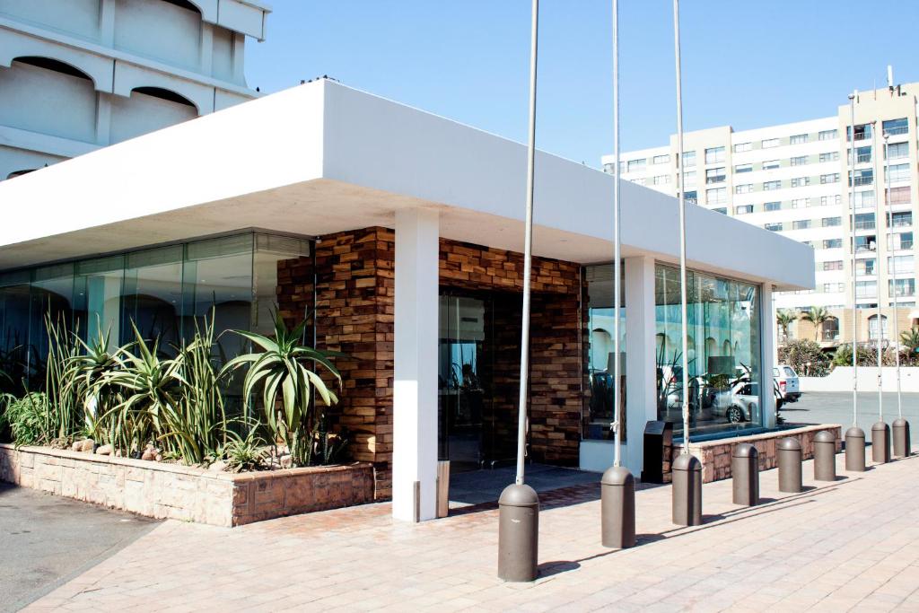 un edificio con ventanas de cristal y plantas delante de él en Beachbreak Holiday Letting, en Durban