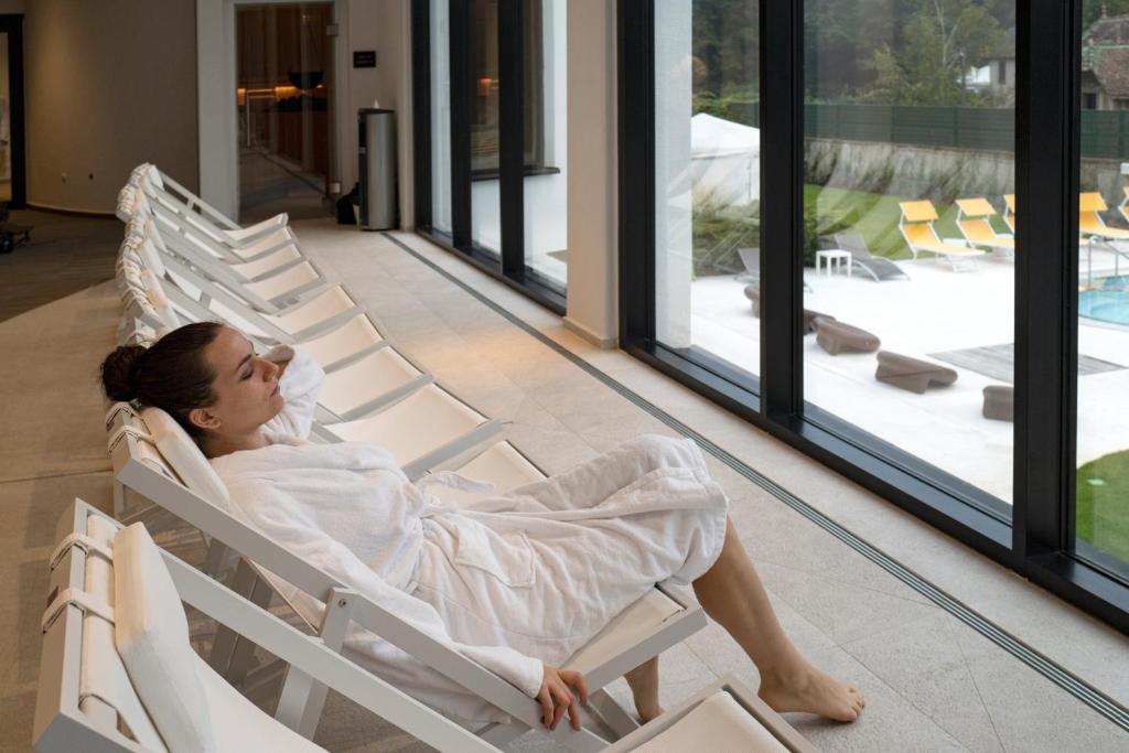 a woman sitting in a rocking chair in a building at 6717 Nature Hôtel &amp; Spa Le Clos des Délices in Ottrott