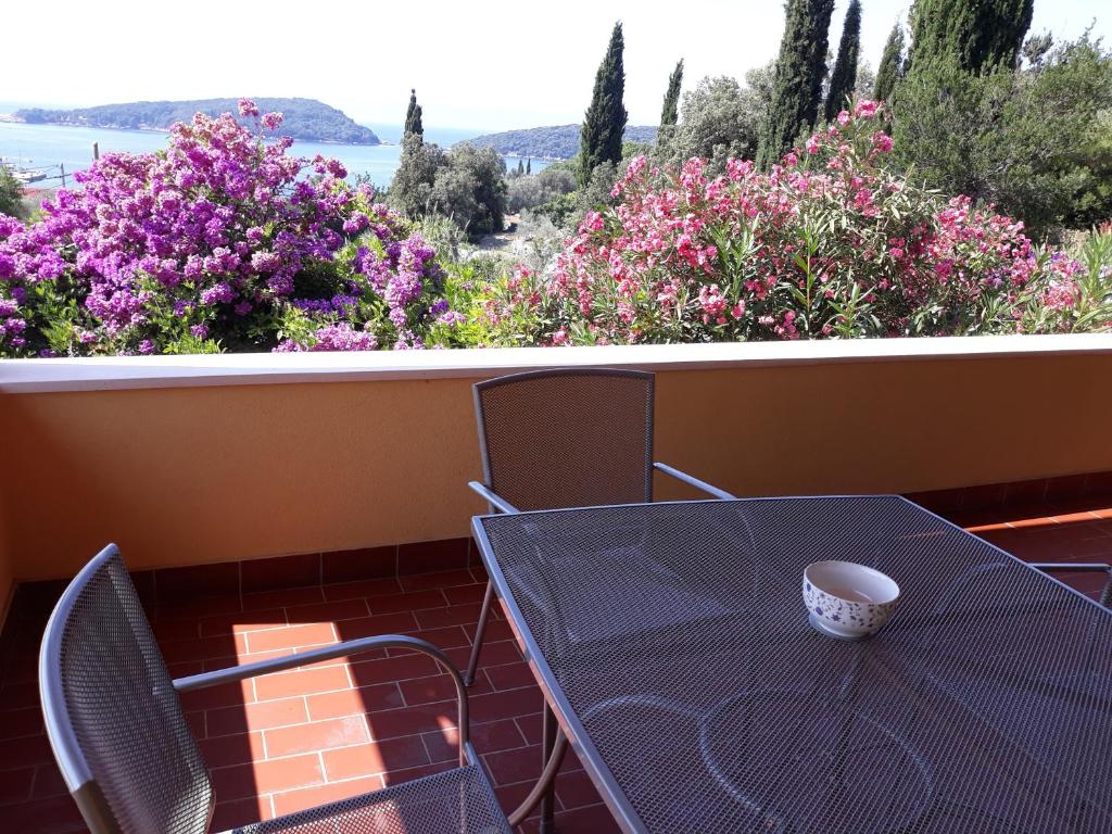 a table and chairs on a balcony with flowers at Apartment Luna in Molunat
