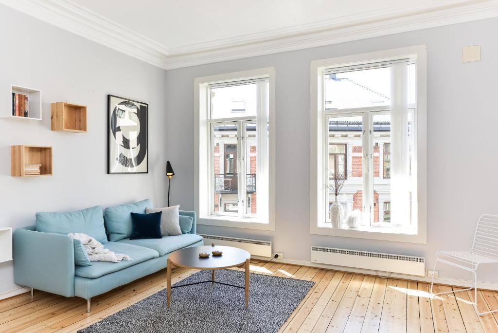 a living room with a blue couch and two windows at Forenom Serviced Apartments Oslo Royal Park in Oslo