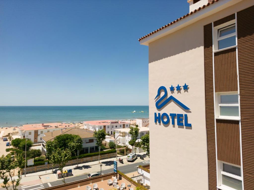 a hotel sign with the ocean in the background at Pato Rojo in Punta Umbría