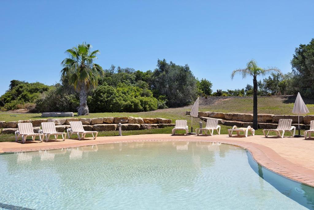 - une piscine avec des chaises et un groupe de palmiers dans l'établissement Pestana Gramacho Residence T2, à Carvoeiro