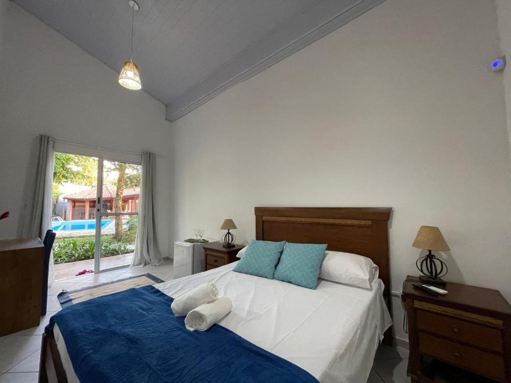 a bedroom with a bed with blue and white pillows at Santa Hospedaria Beach in Bertioga