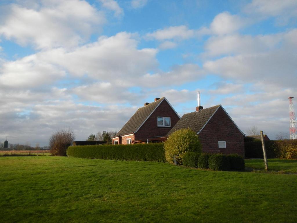 ein Haus auf einem Hügel mit einem grünen Feld in der Unterkunft Frankenhuus in Krummhörn