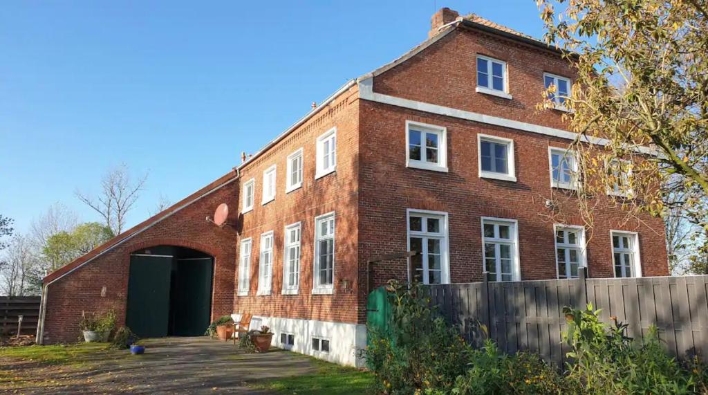 un gran edificio de ladrillo rojo con una puerta verde en Grashaus Leevke, en Krummhörn