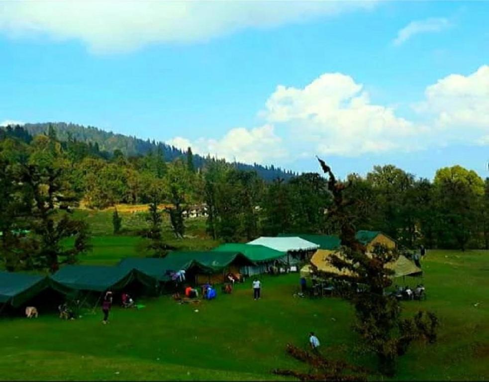 a group of people in a field with tents at Camping at Serene Chopta in Sari